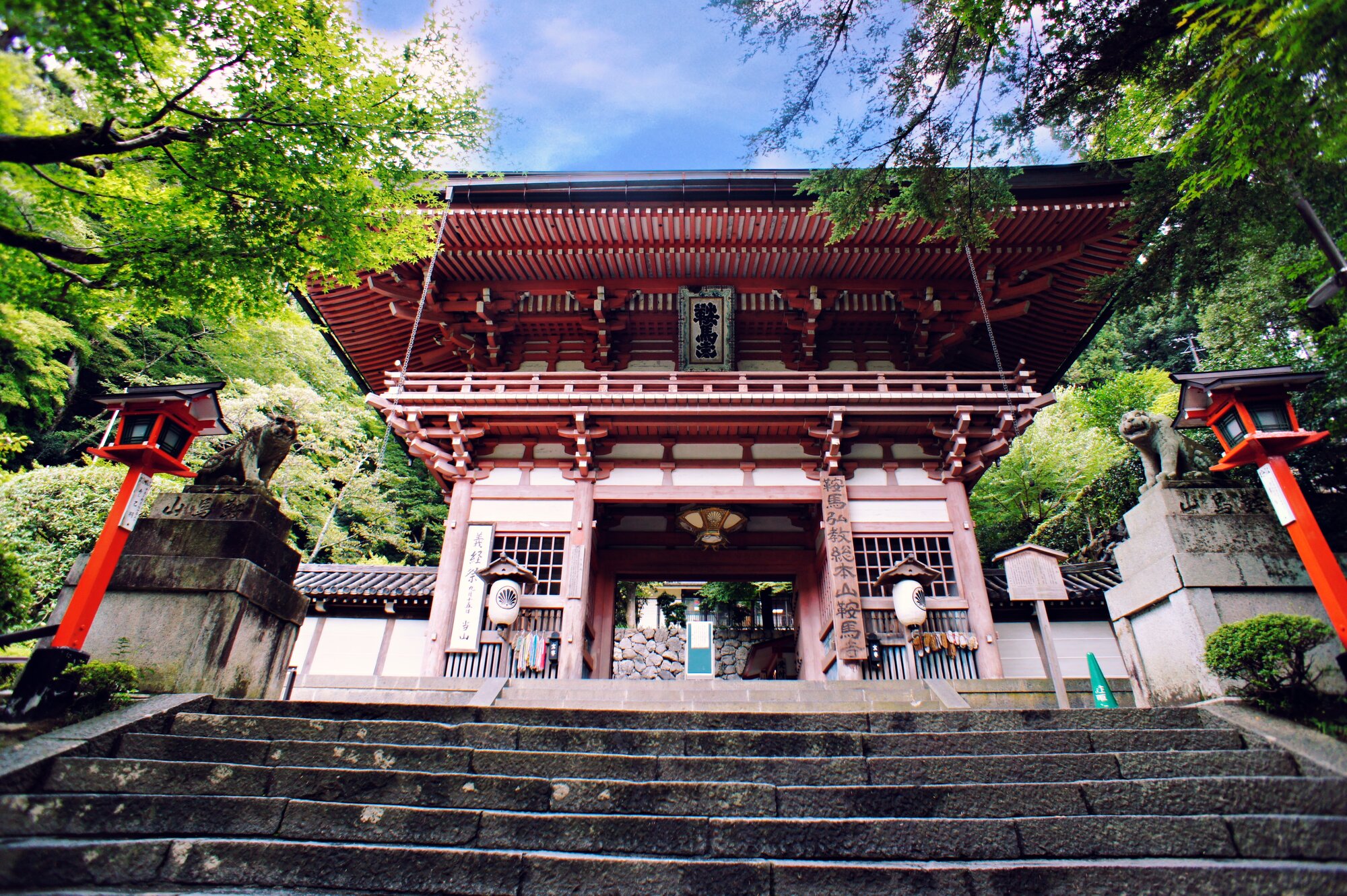 Das rote Niōmon-Eingangstor des Kurama-Tempels bei Kyōto, von unten fotografiert mit steinerner Treppe